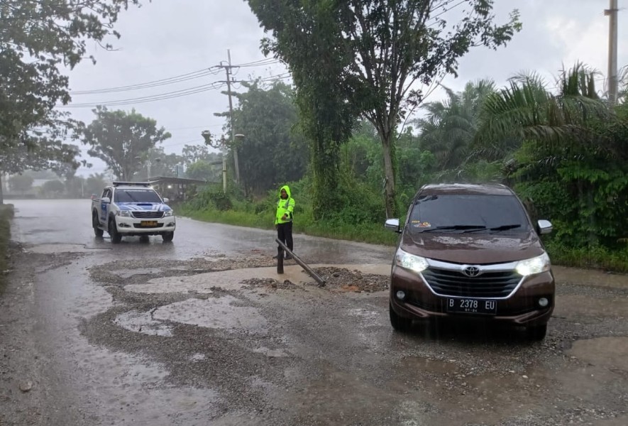 Meski Diguyur Hujan Lebat,Sat Lantas Polres Rohul Pasang Rambu Tanda di Jalan Berlubang